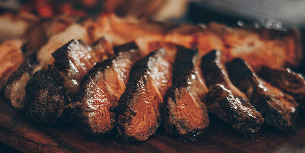 Alderspring Ranch – Sliced steak on a wooden board.